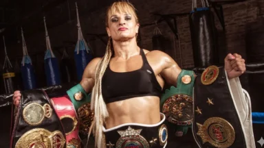 Locomotora Oliveras sosteniendo sus cinturones de campeona mundial de boxeo