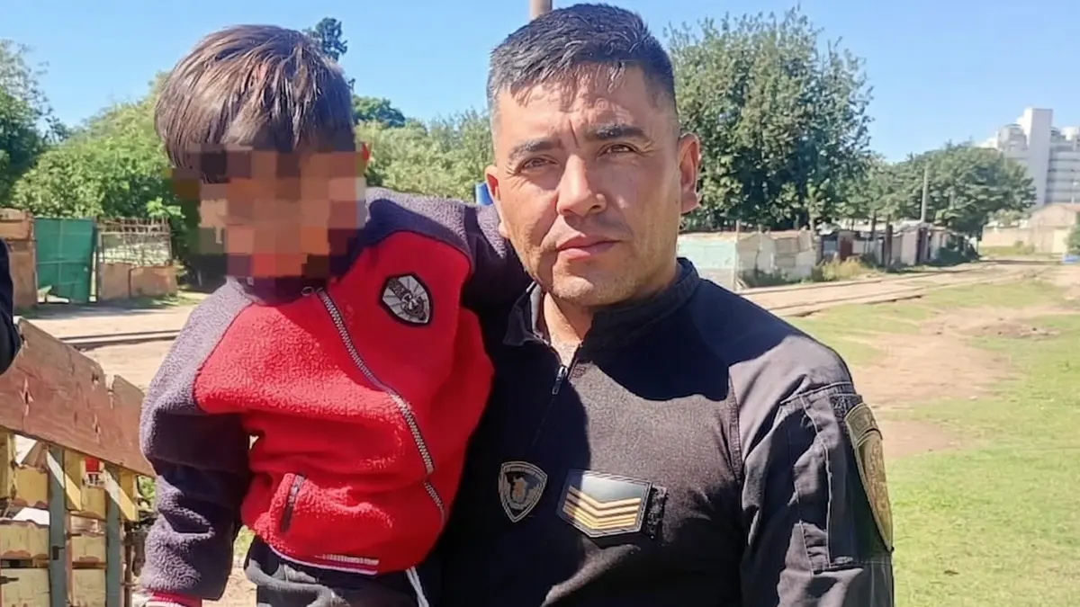 El héroe de la Policía de Córdoba sostiene al niño de 3 años tras salvarlo de ser arrollado por un tren de carga.